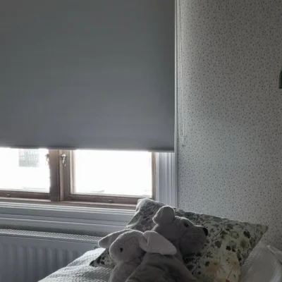 Rullgardin med vit mörkläggande väv och kulkedja på sidan.
